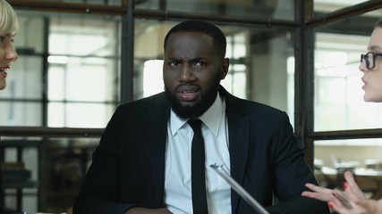 Male boss dissatisfied with co-workers quarrel, raising hands to stop conflict