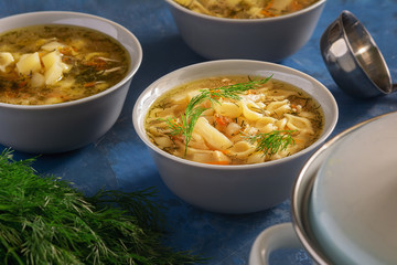 Chicken Noodle Soup with Vegetables Home Recipe. Homemade Healthy First Course Served in White Bowl. Poultry Broth with Traditional Pasta Elevated View. Nutritious Dinner. Tureen and Ladle on Table