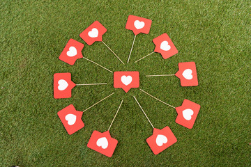 flat lay with social media hearts signs on green field