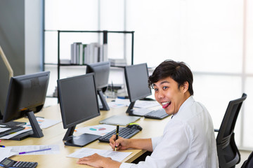 Fototapeta premium Asian man sticking out tongue during working in office