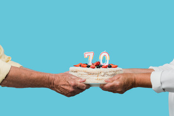 cropped view of retired couple holding tasty birthday cake isolated on blue