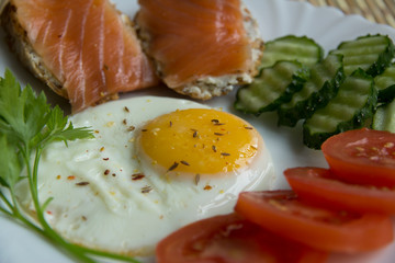 Fried eggs with spices, salmon, tomatoes, cucumbers, parsley