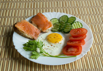 Fried eggs with spices, salmon, tomatoes, cucumbers, parsley
