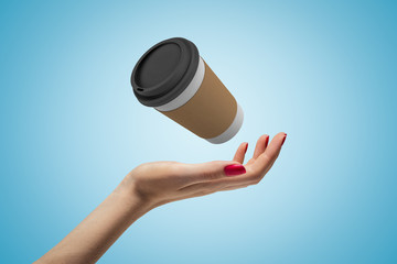 Female hand with coffee paper cup on blue background