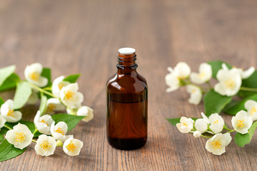 Essential aroma oil with jasmine on wooden background. Massage oil with jasmine flowers. Selective focus. 