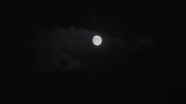 beautiful moon surrounded by clouds floating swiftly through the night sky.