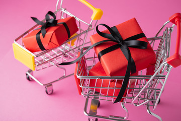 Red gift box with black bow in shopping cart