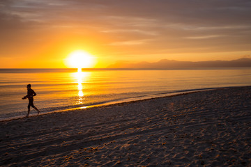 Fototapeta na wymiar Man (Silhouette) running on Mallorca Beach during sunrise, orange