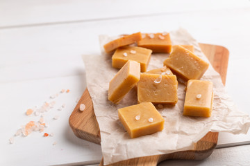 Fresh caramel fudge candies on white rustic background