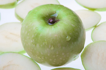 Close up of the green apple with drops and slices