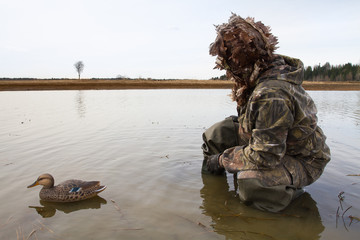 a hunter with a plastic duck decoy in shallow water