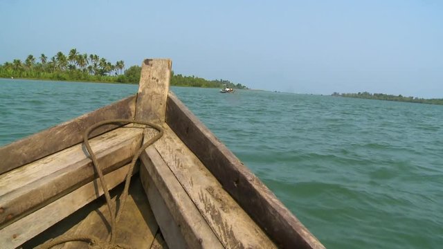 Wide low-angle push-in panoramic dolly shot behind a local kayak boat of blue-green Kangyi River water, and nupa palms forest, Kangyi River, Chaung Thai, Myanmar
