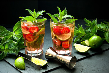 Mojito cool cocktail of lime, mint and strawberry in  glass with ice