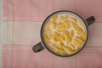 Bowl with Cornflakes and Milk on an wooden table