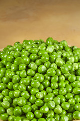 Green peas are piled on a light background. Vertical image.