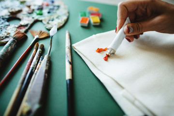 Creative disorder in the work environment. The artist squeezes paint from a tube on the canvas