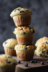 Freshly baked crumble muffins with wild bilberries arranged in unstable pile on dark background copy space. Low key still life with natural lighting