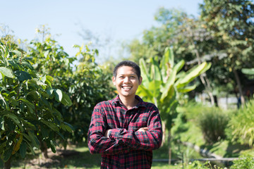 Asian farmer smiling and arms crossed in organic field, Thailand