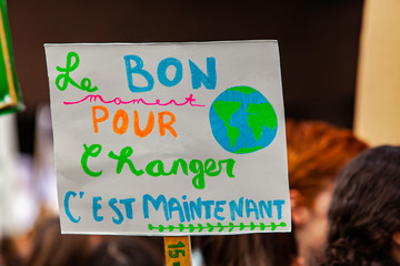 Ecological activist holds French placard. A French phrase on a sign reads the right time to change...
