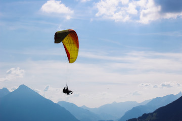Tandem paragliding in Swiss Alps. Silhouettes of paragliders and beautiful mountains. Extreme...