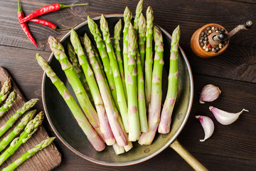 Asparagus in rustic pan on wooden background. Top view