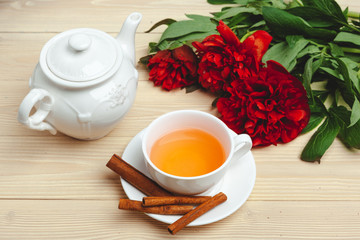 Cup of green tea on table with fresh peony flowers