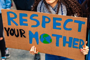 Environmentalist sign at climate rally. A close up shot of a homemade cardboard poster, saying respect our mother, held by a woman during a street protest for environmental issues.