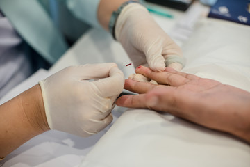 Blood collection staff are using a needle to penetrate the fingertip to check blood sugar levels.