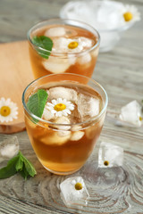 Cups of cold chamomile tea on wooden table