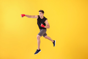 Fototapeta na wymiar Sporty male kickboxer on color background