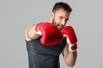 Strong male boxer on grey background