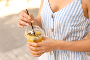 Woman with cup of tasty pineapple juice outdoors, closeup