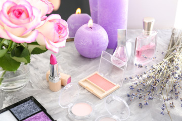 Makeup cosmetics with candles and flowers on dressing table