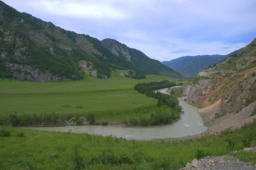 Turquoise Katun, a beautiful mountain river flowing through the fertile valleys surrounded by...
