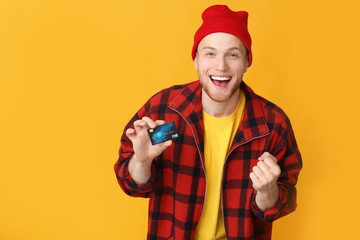Happy young man with credit card on color background