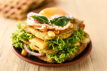Plate with tasty squash waffles and fried egg on wooden table