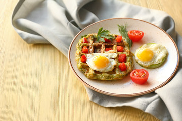 Plate with tasty squash waffles and fried eggs on wooden table