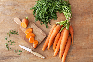 Fresh carrots with knife and cutting board on wooden table