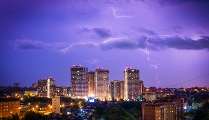 Fototapeta na wymiar Beautiful lightning in the sky at the city at night. Lightning strikes in the dark sky