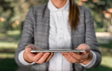 Outdoor scene with business woman holds lap top with touch screen.