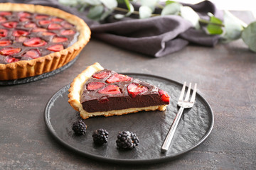 Plate with piece of tasty chocolate strawberry cake on grunge background