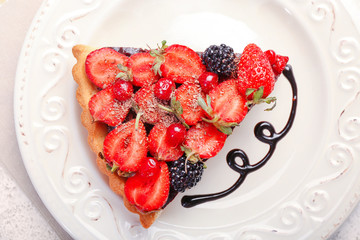 Piece of tasty chocolate strawberry cake on plate, closeup