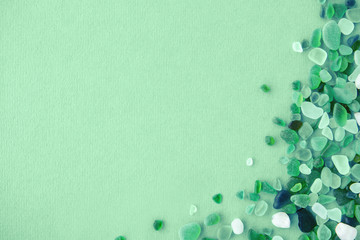 Close up of various sea glass pieces on trendy neo mint background. Design template. Corner frame with copy space for text. Top view, flat lay