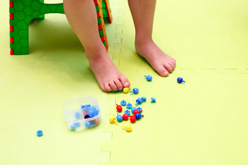 Obraz na płótnie Canvas Kids play with mosaic pieces, glass stones. Orthopedic game, gymnastics with valgus, massage and stimulation of the muscles of the feet