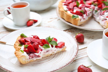 Plate with piece of tasty strawberry cake on table