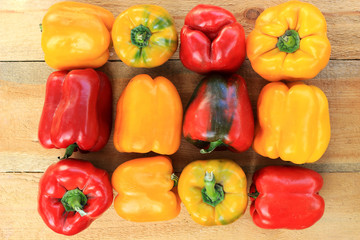 Large ripe, yellow and red bell peppers, on a wooden table.