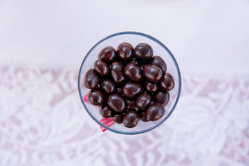 Dark chocolate balls with almond heart. in a glass jar .In a round black chocolate glass . Dark chocolate candy balls in a glass bowl on white background, isolated .