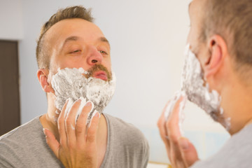 Guy shaving his beard in bathroom