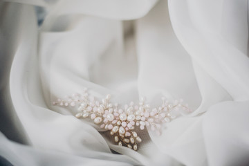 Stylish tender pearl hairpin on soft white tulle in morning light in hotel room. Bridal accessories...