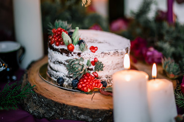 Delicate wedding white cake decorated with pomegranate and succulent surrounded by flowers and...